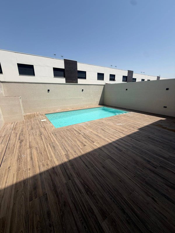 Piscina de obra en un patio cerrado rodeada de pavimento porcelánico efecto madera